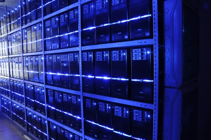 Corredor de um centro de dados com filas de servidores iluminados a azul