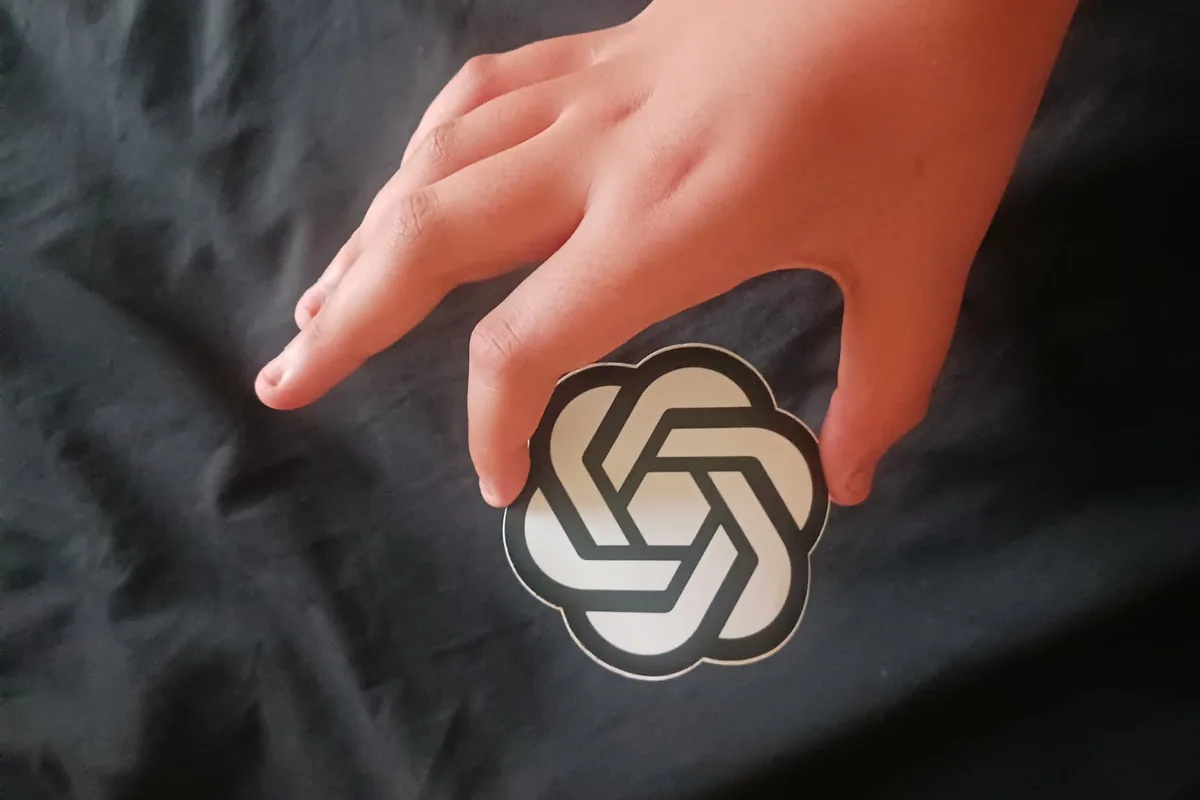 Mão a segurar um objeto com o sÃmbolo da OpenAI