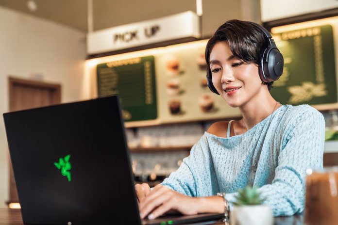 Utilizadora com os Razer Barracuda V2 Pro ao computador num café